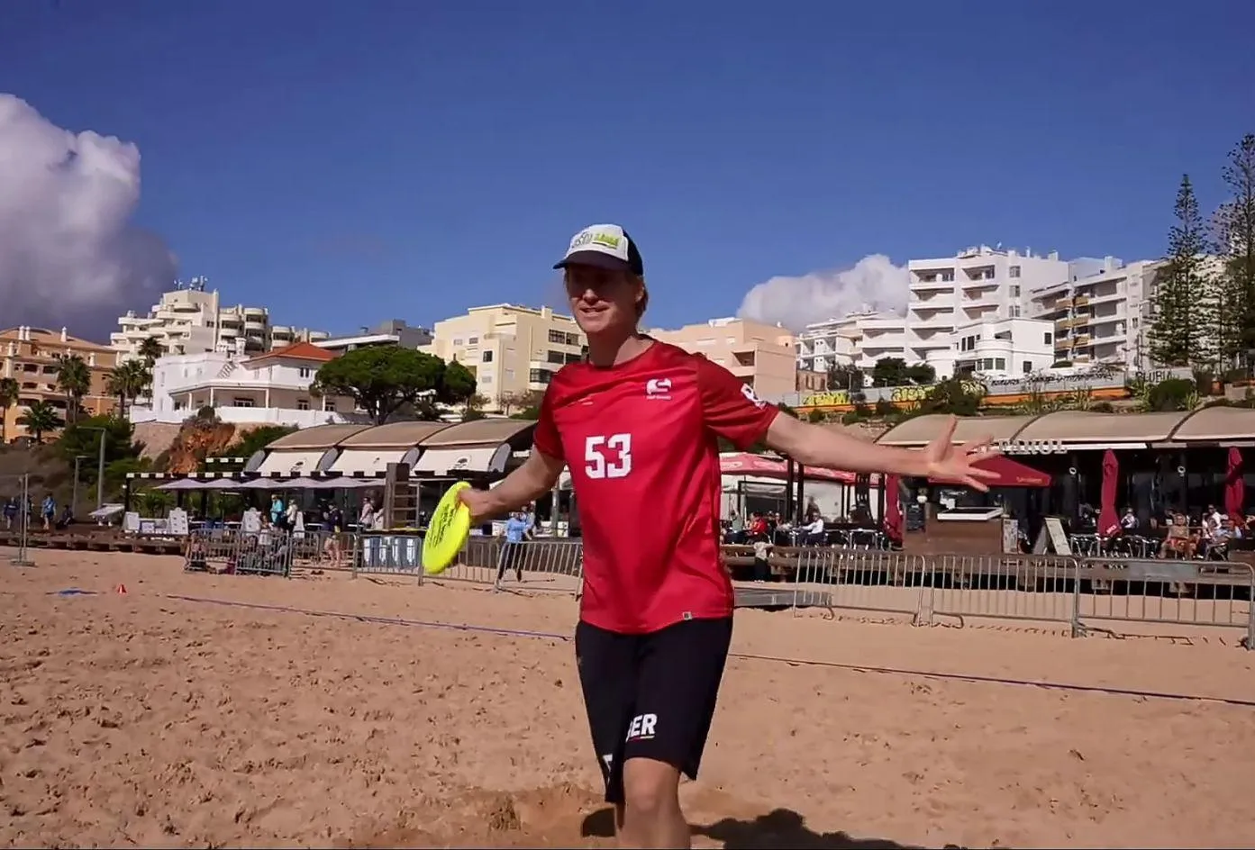Frisbeespieler auf Sand, der eine Scheibe gefangen hat und sich freut